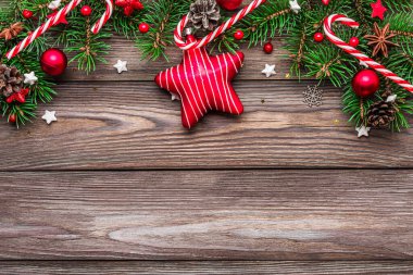 Köknar ağacı dalları, kırmızı süslemeler, kırsal ahşap masa üzerinde şeker ve çam kozalakları olan bir Noel arkaplanı. Düz yatıyordu. Mutlu yıllar ve kış tatilleri planı. Kopyalama alanı olan üst görünüm.