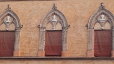 Tarihi binanın dış cephesinde Gotik tarzı mimari detaylar, kemerli pencereler, Bologna 'daki Piazza Santo Stefano' nun büst heykelleri, gün doğumunda İtalya 'nın Emilia Romagna kentinde..