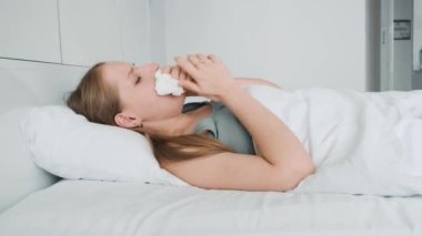 Nezle ve nezle olmuş, hapşıran ve yatakta yatan mendile öksüren hasta bir kadın. Hastalıklı kız baş ağrısı çekiyor, burnunu siliyor ve yatak odasında ilaç içiyor. Sağlık hizmeti kavramı.