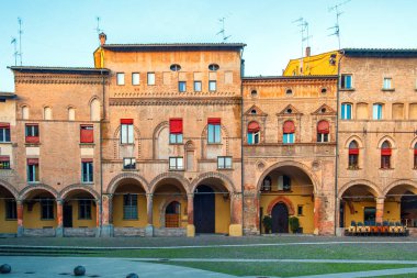 Facade of a historic building with arched porticoes, red shutters and medieval architectural details on Piazza Santo Stefano in Bologna old town, Emilia Romagna, Italy at sunrise with nobody. Travel clipart