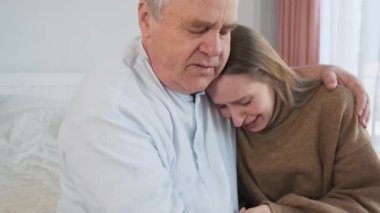 Yaşlı babayı sevmek, ağlayan yetişkin kızı teselli etmek, yatakta otururken başını okşamak. Aile desteği ve ilişki, ilgi ve ebeveynler konsepti sever.