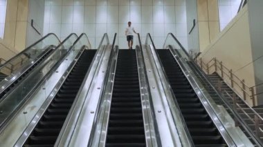 Adam modern metro, metro ve tren istasyonlarında metal ve cam mimarisi olan yürüyen merdivenlere biniyor. Kentsel modern ulaşım kullanan bir erkek yolcu. Kentsel yaşam tarzı, ulaşım ve hareket kavramı.