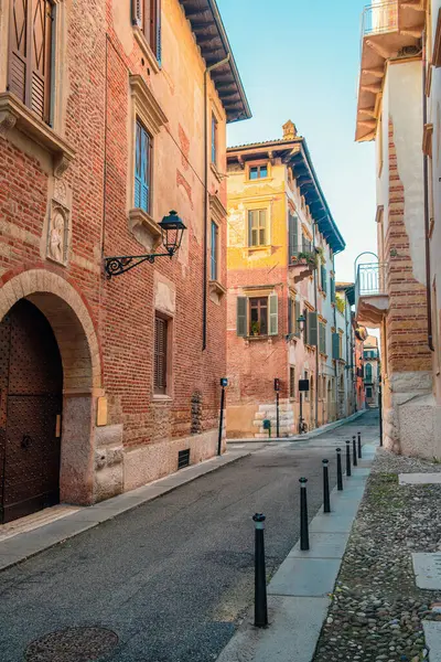 Gündoğumunda İtalya 'nın Veneto kentindeki Verona eski kasabasında tarihi tuğla binalar ve kaldırımlarla dolu ortaçağ dar sokakları. İtalyan caddesinde kimse yok. Dikey oryantasyon. Gidilecek yer