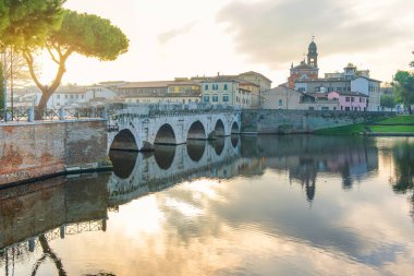Marecchia nehrinin üzerinde Tiberius Köprüsü olan Rimini kasabası, gün doğumunda, Emilia-Romagna, İtalya. Ortaçağ mimarisi ve Ponte di Tiberio ile İtalyan şehri. Turizm ve seyahat beldesi.