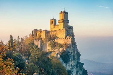 Guaita Kulesi, San Marino 'nun üç kulesinden biri, sisli günbatımında Monte Titano kayasına tünemişti. San Marino 'daki ortaçağ kalesi. Avrupa 'da seyahat ve turistik dönüm noktası.