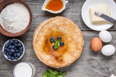 Yaban mersinli, nane ve ballı bir yığın ince krep. Fransız krepleri, süt ve tereyağı ve ahşap masada lezzetli bir kahvaltı. Üst Manzara. Lezzetli yemek..