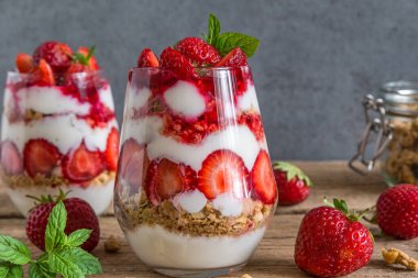 Çilekli yoğurt parfe, granola ve taze nane şekeri. Kırsal ahşap masada, tam böğürtlenli. Sağlıklı kahvaltı. Lezzetli yemek..