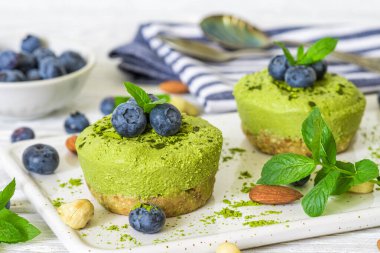 Yaban mersinli kiraz vejetaryen peynirli kekler ve fındıklı nane şekeri ve yeşil çay tozu. Taze böğürtlenli çiğ vejetaryen kekleri. Sağlıklı vejetaryen tatlı. Kapat.