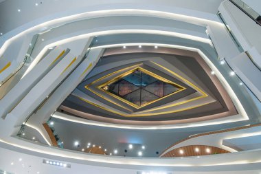 Fütüristik mimarisi ve katmanlı geometrik tavanı olan modern alışveriş merkezinin iç manzarası farklı seviyelerde. Modern alışveriş merkezi simetri, perspektif, soyut mimari.