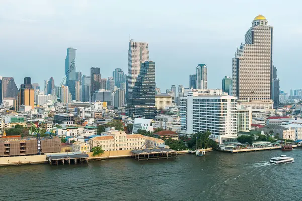 Günbatımında teknesi olan Chao Phraya nehrinin kıyısında, gökdelenleri olan modern şehir silueti, Tayland. Modern Asya şehir manzarası.