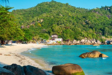 Turkuaz su okyanusuyla tropik kumlu sahil, yemyeşil kayalık kıyı şeridi ve berrak mavi gökyüzü altında deniz kenarındaki villalar. Tayland 'daki Koh Samui adasındaki Crystal Bay kumlu plajı. Yaz tatili