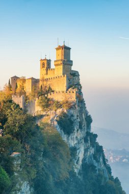 Guaita Kulesi, San Marino 'nun üç kulesinden biri, sisli günbatımında Monte Titano kayasına tünemişti. San Marino 'daki ortaçağ kalesi. Dikey oryantasyon. Seyahat ve turistik dönüm noktası