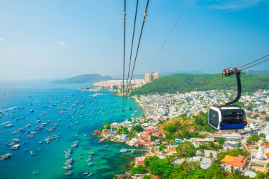 Renkli evleri, balıkçı tekneleri, turkuaz deniz ve Vietnam 'daki Phu Quoc adasındaki modern teleferik yolculuğunun olduğu kıyı balıkçıları köyünün havadan görünüşü. Modern Hon Thom teleferik kulübesi. Turizm