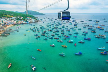 Dünyanın en uzun teleferik yolculuğu Phu Quoc adası, Vietnam 'da turkuaz denizde ve aşağıda kıyı balıkçı köyünde demirli balıkçı tekneleriyle. Modern Hon Thom teleferik kulübesi. Hava görünümü.