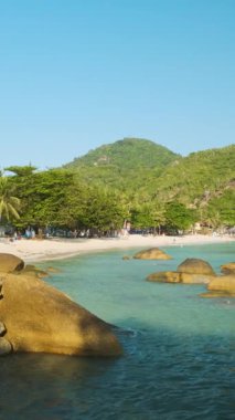 Turkuaz su okyanusuyla tropik kumlu sahil, yemyeşil kayalık kıyı şeridi ve berrak mavi gökyüzü altında deniz kenarındaki villalar. Tayland 'daki Koh Samui adasındaki Crystal Bay kumlu plajı. Dikey yönelim