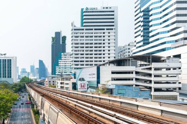 Bangkok, Tayland - 19 Mart 2025: Bangkok 'ta yüksek binaları ve şehir trafiği olan modern şehir merkezine uzanan yüksek tren rayları. Kentsel hareketlilik ve modern altyapı