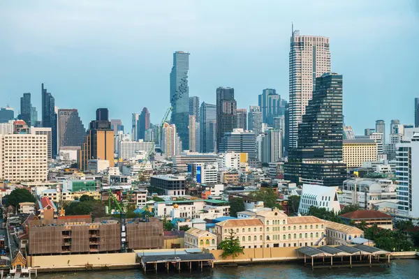 Günbatımında Chao Phraya nehrinin kıyısında, gökdelenleri ve orta katlı binaları olan Bangkok şehrinin modern şehir silueti. Modern Asya şehir manzarası.