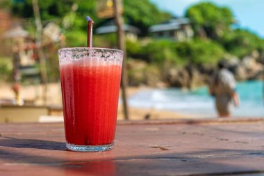 Tayland 'daki Samui Adası' ndaki sahil kafesinde, ahşap bir masa üzerinde, cam içinde kırmızı karpuz smoothie tazeliyorum. Coral Cove sahilindeki yaz restoranında soğuk tropik meyve suyu..