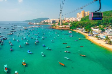 Balıkçı tekneleri, turkuaz deniz ve Vietnam 'daki Phu Quoc adasında teleferik yolculuğu yapan balıkçı köyünün havadan görüntüsü. Modern Hon Thom teleferik kulübesi. Turizm altyapısı.