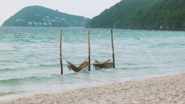 Beyaz kumlu tropik plaj, turkuaz deniz ve tahta kutuplar arasında süzülen iki hamak, Phu Quoc adası, Vietman. Khem plajı. Asya 'da yaz tatili.