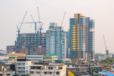 Bangkok şehrinin gökdelenleri, yüksek binaları, inşaat halindeki gökdelenleri, yukarıda yükselen vinçleri, modern apartmanları, karışık mimarisi olan gökdelenleri. Tayland 'daki Asya şehir manzarası. Ekonomik gelişme