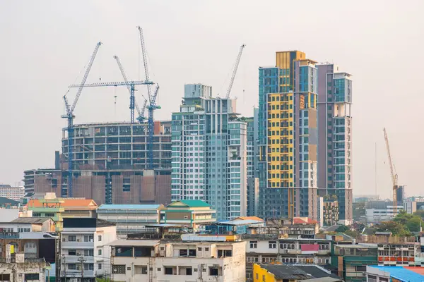 Bangkok şehrinin gökdelenleri, yüksek binaları, inşaat halindeki gökdelenleri, yukarıda yükselen vinçleri, modern apartmanları, karışık mimarisi olan gökdelenleri. Tayland 'daki Asya şehir manzarası. Ekonomik gelişme