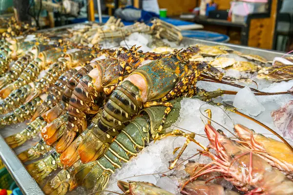 Taze ıstakoz ve kaplan karidesleri süpermarketteki ezilmiş buz üzerinde satılık deniz ürünleri tezgahında sergileniyordu. Tayland 'da marketin rafında soğuyan dev karidesler. Gıda alışverişi ve perakende.