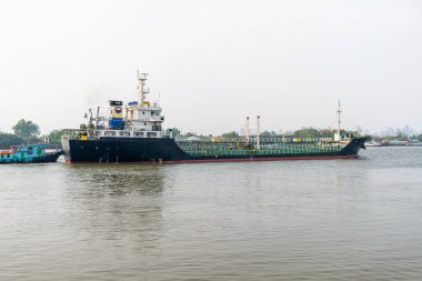 Bangkok, Tayland 'da Chao Phraya Nehri' nde büyük bir kargo gemisi. Yanında küçük bir römorkör ve karmaşık ekipmanlı bir sanayi gemisi var. Petrol tankeri. Endüstriyel deniz lojistiği ve enerjisi