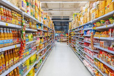 Phuket, Tayland - 20 Mayıs 2025: Tayland 'da paketli mallar, şişe soslar, baharatlar ve aperatiflerle dolu bir süpermarket koridoru. Gıda tedarik zinciri, perakende şirketi.