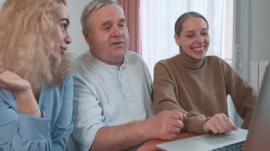 Evde dizüstü bilgisayar izlerken gülen iki kızı olan mutlu yaşlı bir baba. Aile bağları, duygusal sıcaklık, çok nesilli ilişkiler, modern aile teknolojisi kullanımı, duygusal