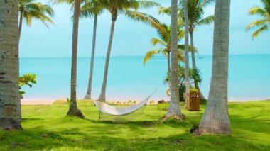 Tropik sahildeki palmiye ağaçlarının arasında asılı duran turkuaz deniz ve yeşil çimenler, rahatlamaya, yaz tatiline ve huzurlu kaçışa hazırlanan cennet, Phu Quoc Adası, Vietnam
