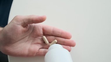 İlaç şişesinden bej probiyotik kapsüller döken adam. Besin takviyesi. Mide sağlığı, günlük sağlık rutini, sindirim desteği, bağışıklık sisteminin geliştirilmesi ve mikrobiyomda denge
