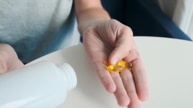 Balık yağı, omega3 ve ilaç şişeli vitamin takviyeli iki yumuşak jel kapsülü tutan bir adam. Besin takviyesi. Sağlık desteği ve tedavi konsepti. Üst Manzara. Sağlık, önleyici