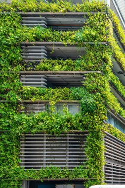 Bangkok, Tayland 'da sürdürülebilir şehir mimarisini destekleyen yemyeşil bitkiler ve dikey bahçelerle modern bina cephesi. Çevre dostu şehir ortamı. Sürdürülebilir tasarım ve
