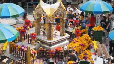 Bangkok, Tayland - 20 Mart 2025: Bangkok 'ta insanların çiçek düzenlediği, adak adadığı, dua ettiği ve mavi şemsiyeler altında çelenk taktığı kalabalık bir sokak tapınağı. Tayland dini bağlılığı.