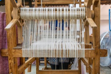 Tayland, Chiang Mai 'deki ipek fabrikasında kumaş dokumak için kullanılan beyaz ipek ipliklerle geleneksel ipek dokuma tezgahı. El yapımı işçilik, tekstil üretimi sanatı, sürdürülebilir.