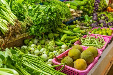 Markette satılmak üzere sepetlerde sergilenen çeşitli taze sebzeler ve tropikal meyveler. Phuket, Tayland 'da çeşitli yeşillik, salatalık, patlıcan, uzun fasulye ve yeşil Noel Baba çeşitleri.