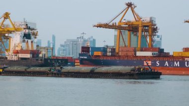 Bangkok, Tayland - 21 Şubat 2025: Büyük kargo gemileri, Chao Phraya Nehri 'nde düz mavna ve küçük römorkör taşıyan konteynırları yükleyen sarı konteynırların altına yanaştı