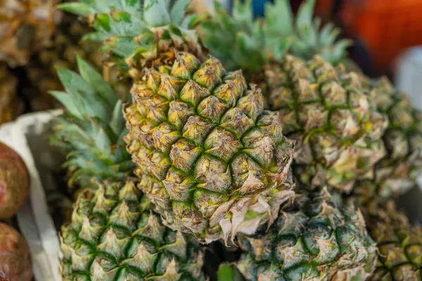 Markette sergilenen yeşil taçlı taze ananaslar. Tayland 'daki Phuket pazarında renkli tropikal meyveler. Kapat.