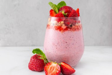 Çilekli puding üzerine taze çilek, granola ve beyaz arka planda bir bardakta nane şekeri. Chia tohumlu çilekli yoğurt. Sağlıklı kahvaltı. Lezzetli yemek..