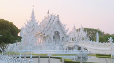 Beyaz tapınak Wat Rong Khun çevresi yemyeşil bahçe ve gün batımında gölet ile çevrili, Chiang Rai, Tayland. Kuzey Tayland 'daki Budist tapınağı. Asya 'da seyahat ve turistik dönüm noktası.