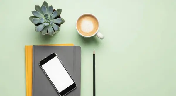 A minimalist workspace flat lay featuring a cup of coffee, succulent, notebook, and smartphone. Perfect for blog, social media, and marketing content. Clean and modern.