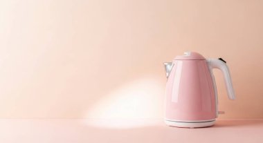 A pink electric kettle is on a pink background. There is copy space on the left. The kettle is modern and stylish. The background is a pastel color. The kettle is empty.