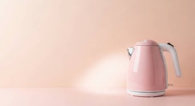 A pink electric kettle sits on a pastel pink surface, offering ample copy space. This modern appliance is perfect for tea, coffee, and hot water preparation.