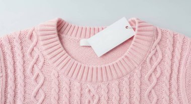 A close-up shot showcases a pink knitted sweater with a blank tag, ideal for fashion, retail, or holiday-themed projects. Isolated on a white background.