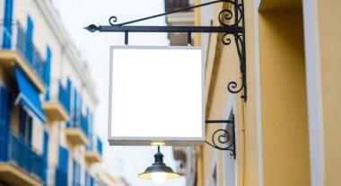 Şehir caddesindeki bir binanın duvarında boş bir kare tabela asılı, reklam için fotokopi alanı sunuyor. Kentsel ortam ve mimari ayrıntılar görsel ilgi ekliyor.