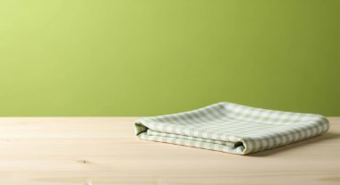 Katlanmış çizgili keten peçete, yeşil bir arka plana karşı ahşap bir masanın üzerine yerleştirilir. Sahne basit, temiz ve kırsal, yemek sunumu ve tasarım için mükemmel..