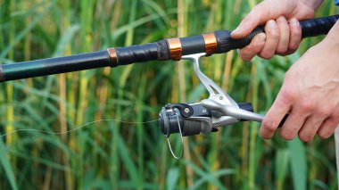 Balıkçı gölde olta tutuyor. Balık tutmaya. Balıkçı oltası ve olta kamışının yakın çekimi. Döndürme.