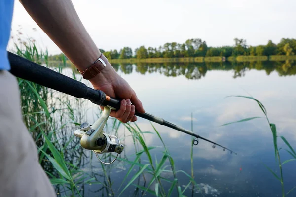 stock image Fisherman holding fishing rod at the lake. Fishing. Closeup of hand holding fishing rod and fishing reel.