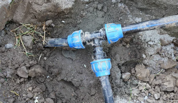 Yerin altına mavi plastik su boruları yerleştirilmiş. Su borularının kurulumu.